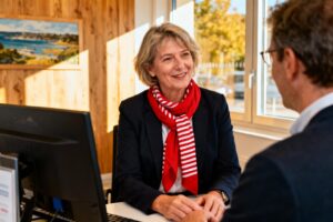 Conseillère financière souriante portant une écharpe bretonne rouge discute avec un client dans une agence Crédit Mutuel