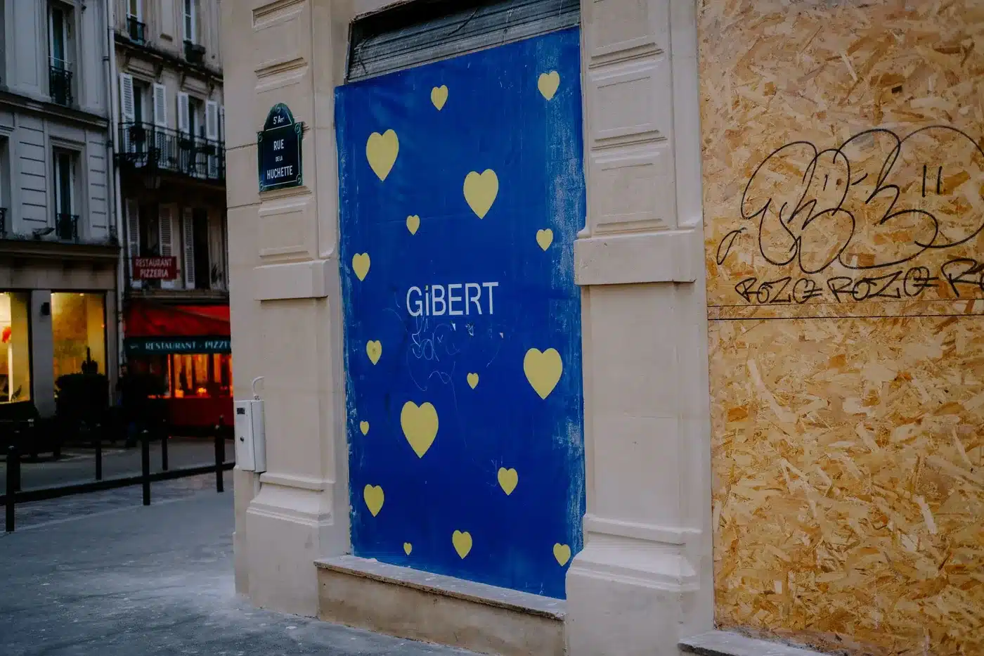 Un magasin fermé avec une façade recouverte de graffitis et une signalisation de rue dans un cadre urbain.